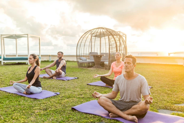 a group of people doing yoga outdoors at sunset