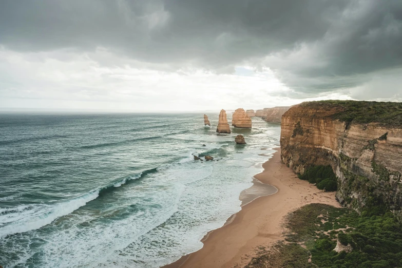 people are standing on the cliff overlooking the ocean and cliffs