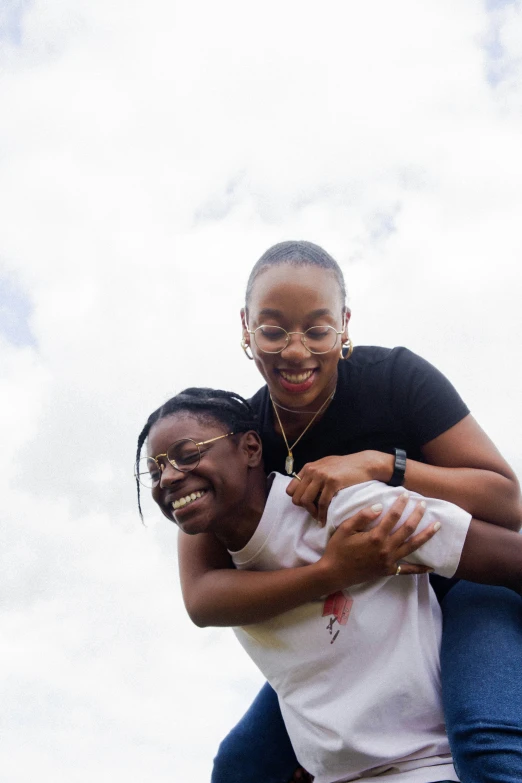 two women laughing together with a sky background