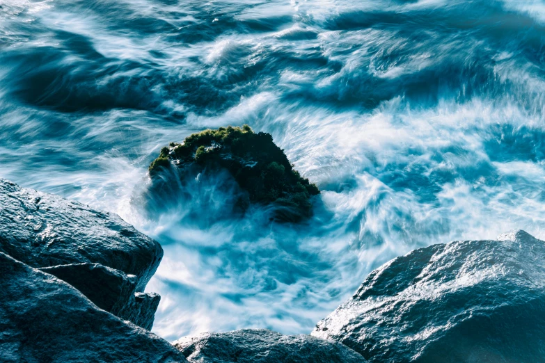 a rock formation in rough seas on a clear day