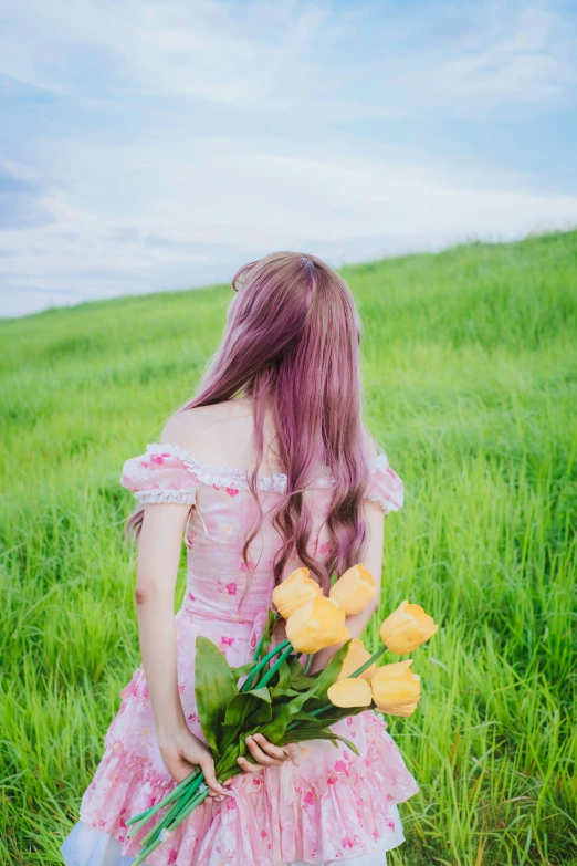 girl in pink dress holding roses near grassy area