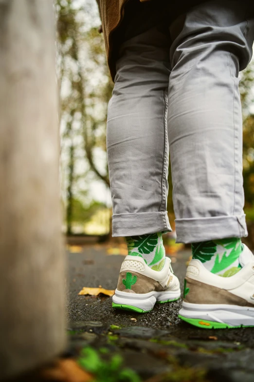 the feet of someone wearing green and white sneakers