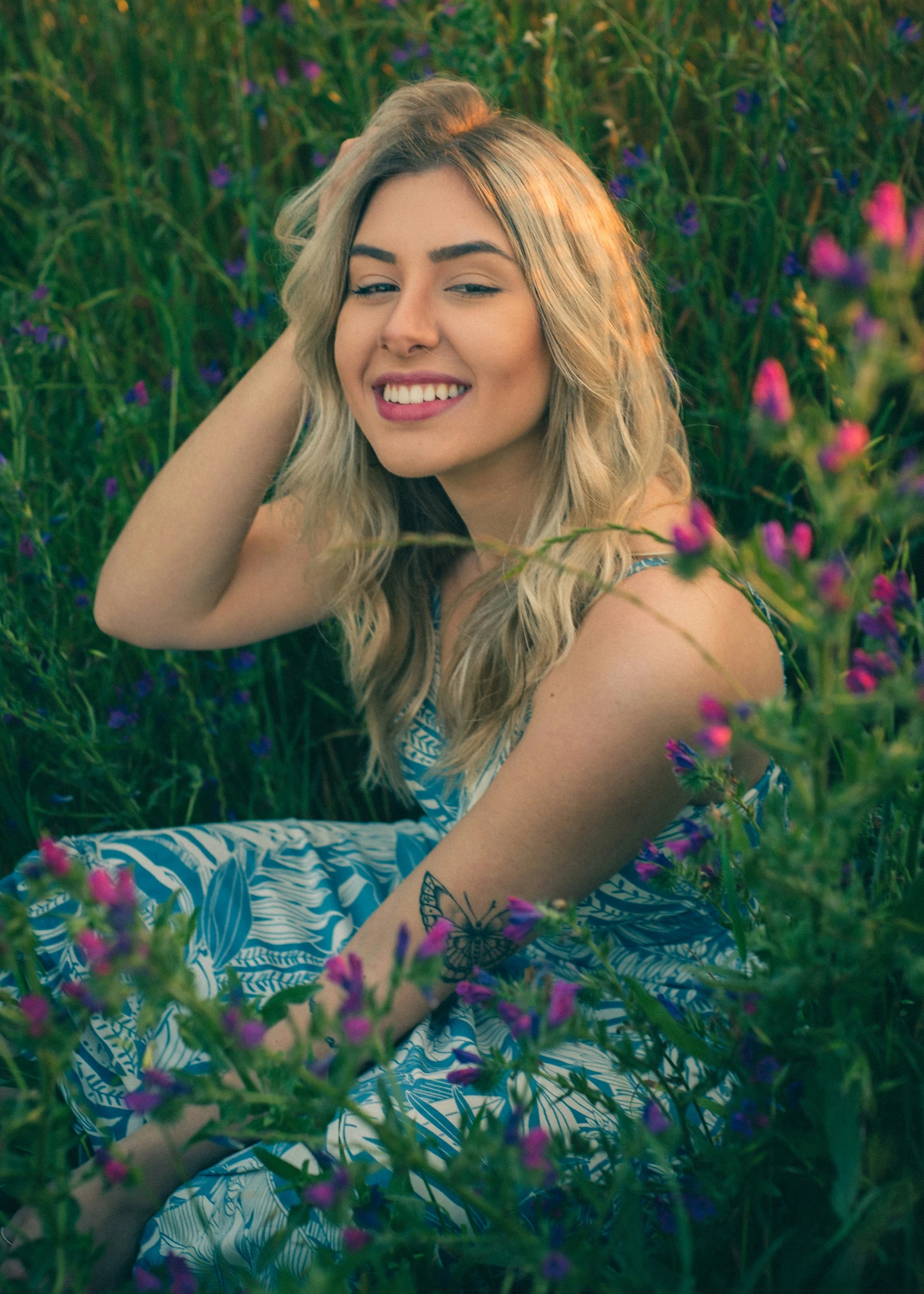 a woman sitting in tall grass with purple flowers