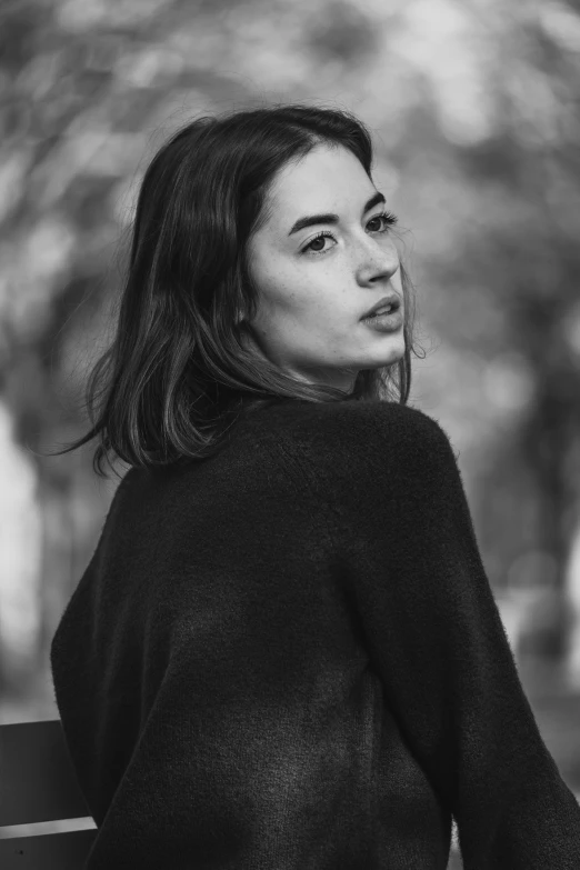 a woman with her hair blown in the wind sitting on a park bench