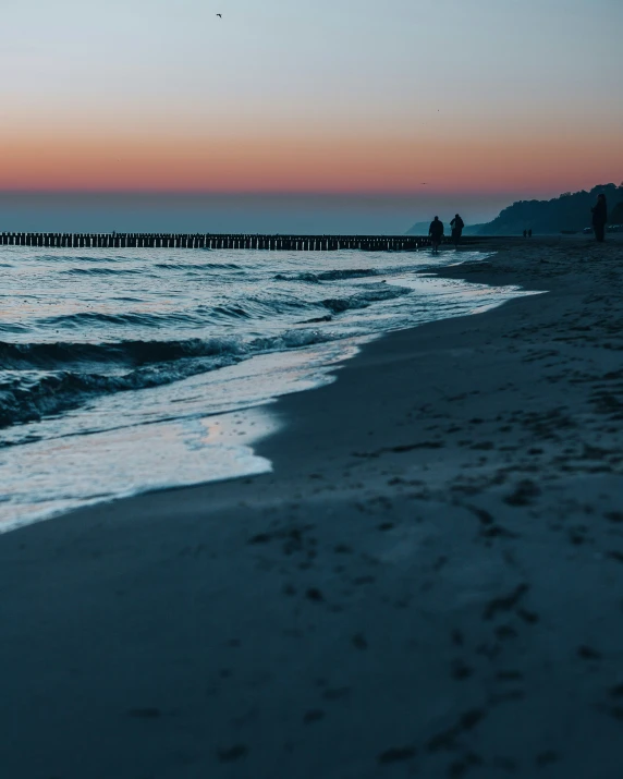 people walking in the sand near the ocean