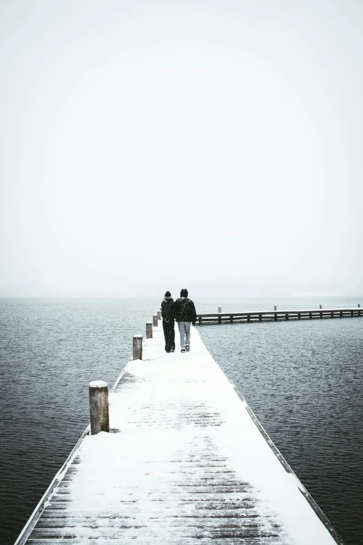 two people stand on a dock in a snow - covered place