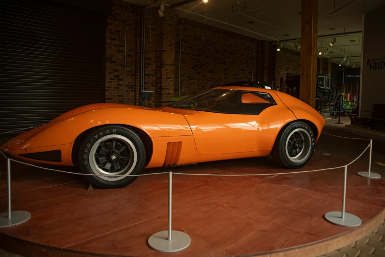 an orange sports car on display next to some metal posts