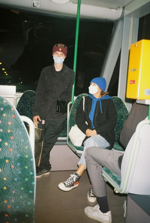 the couple on a bus ride are wearing face masks