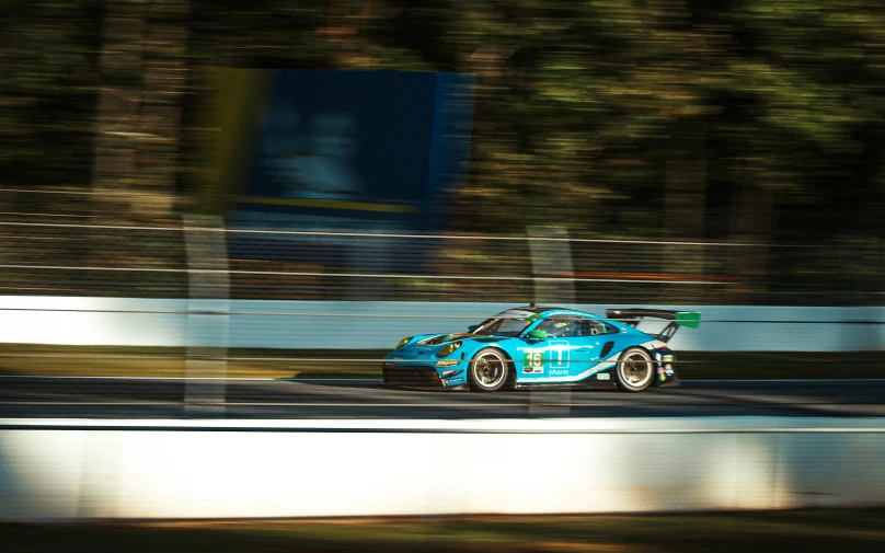 a racing car driving on a road near trees