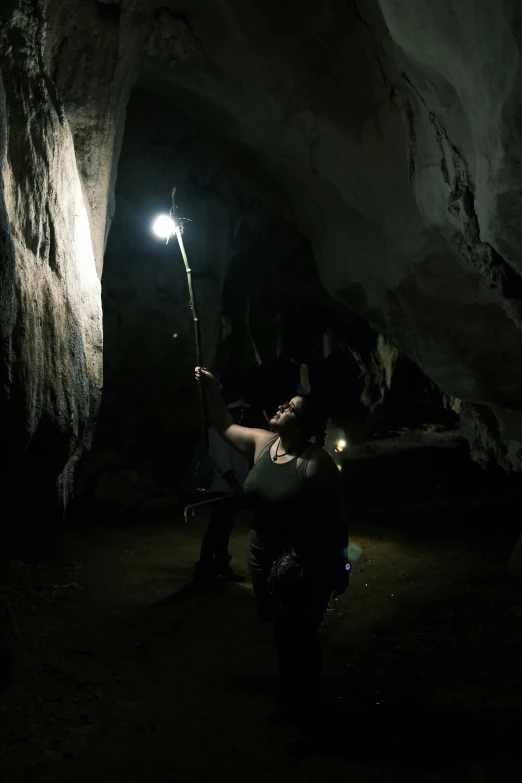 person looking at a flashlight in a dimly lit cave