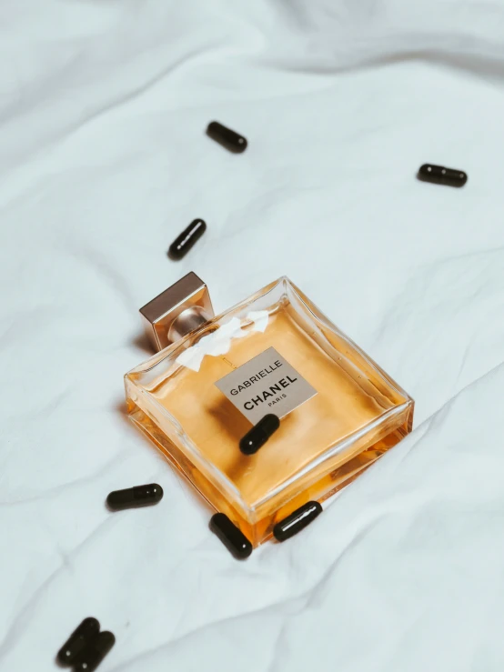 an open bottle of perfume sitting on top of a bed