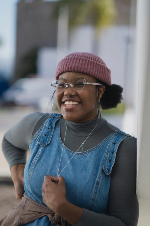 a woman smiling with glasses and a beanie on her head