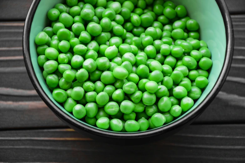 a metal container filled with green peas on a table