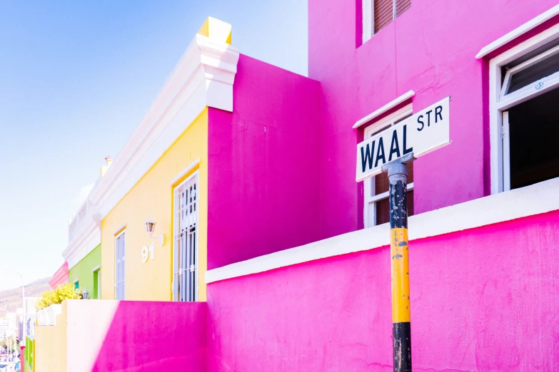 a pink building has a white wall street sign