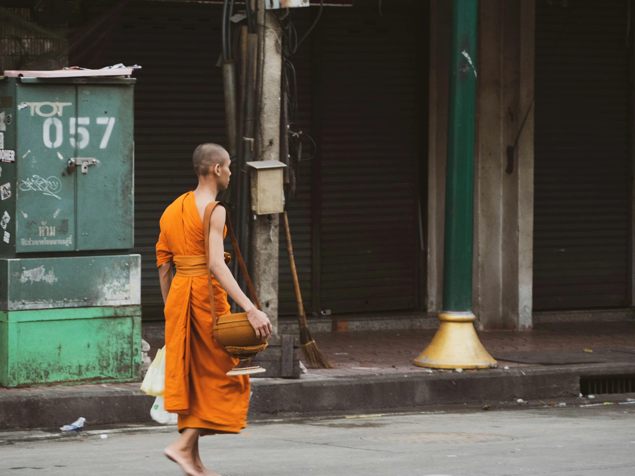 a man in an orange robe is holding a baseball on the sidewalk