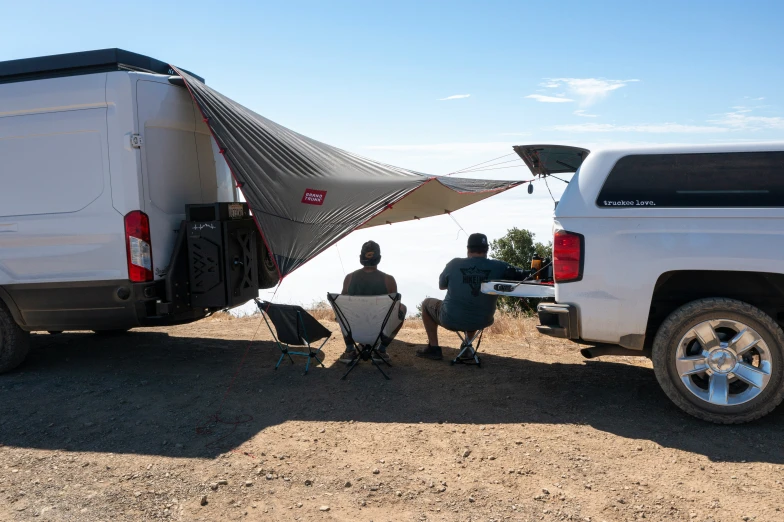 a man sitting next to a white truck with his camper