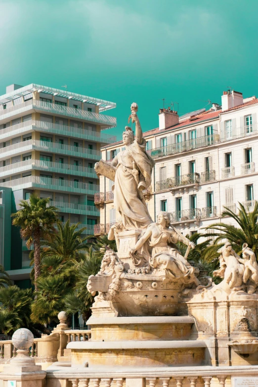 a statue on top of a fountain surrounded by trees