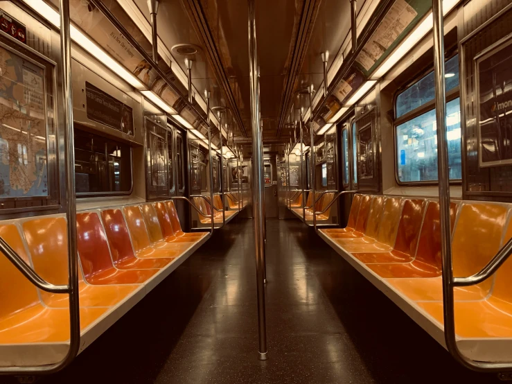 the subway car has an orange seat next to the window