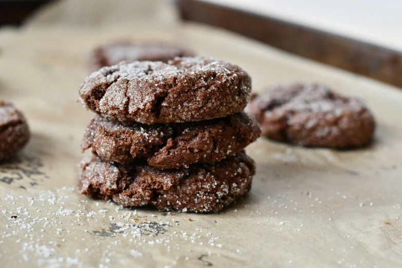 chocolate cookies covered in powdered sugar next to a cookie sheet