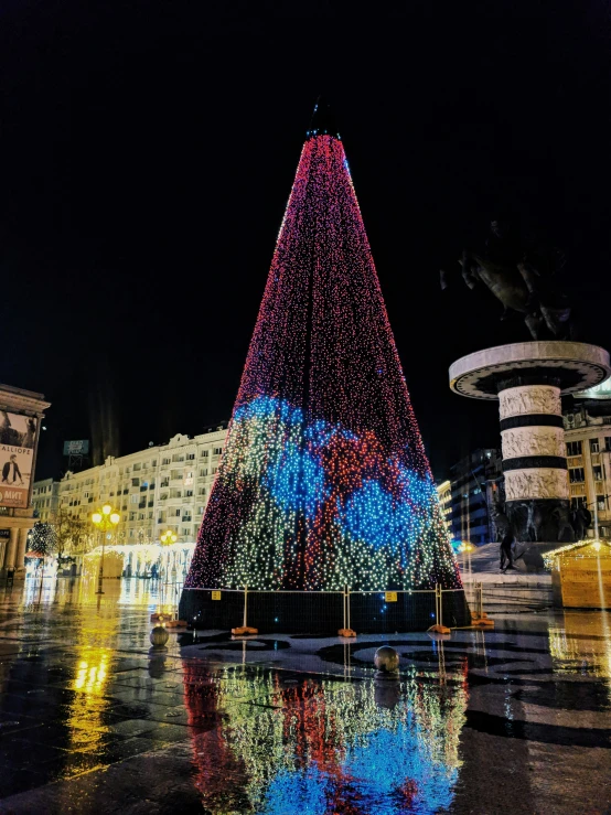 a christmas tree on a plaza surrounded by buildings