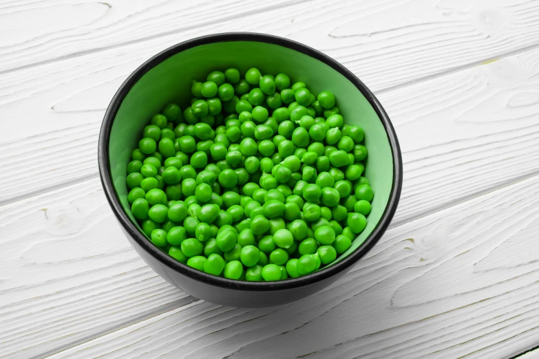 a green bowl filled with lots of green peas