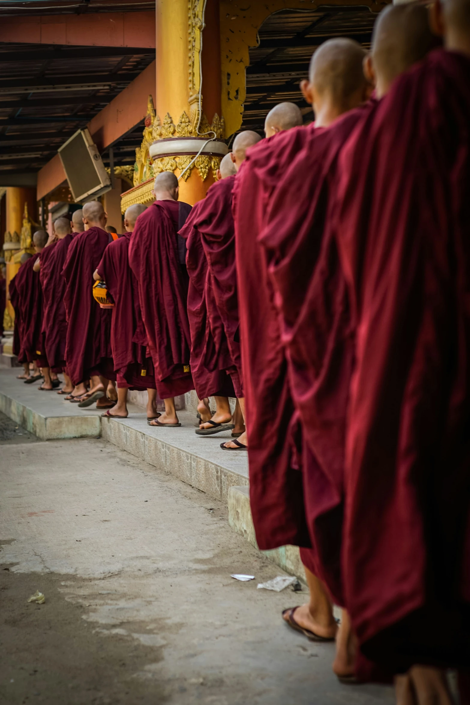 a line of monks walking across a walkway