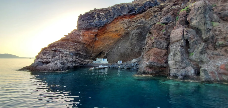 a cliff side overlooks a deep turquoise ocean with white houses at the top