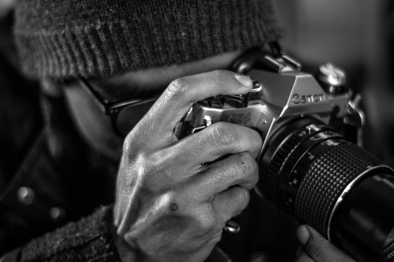 man holding camera taking pos while wearing a hat