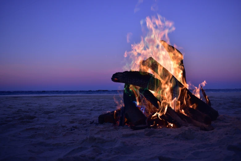 the fire is blazing in the sand near the beach