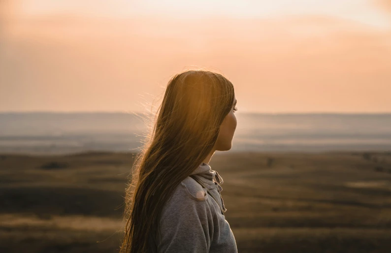 a woman with long hair standing in a field