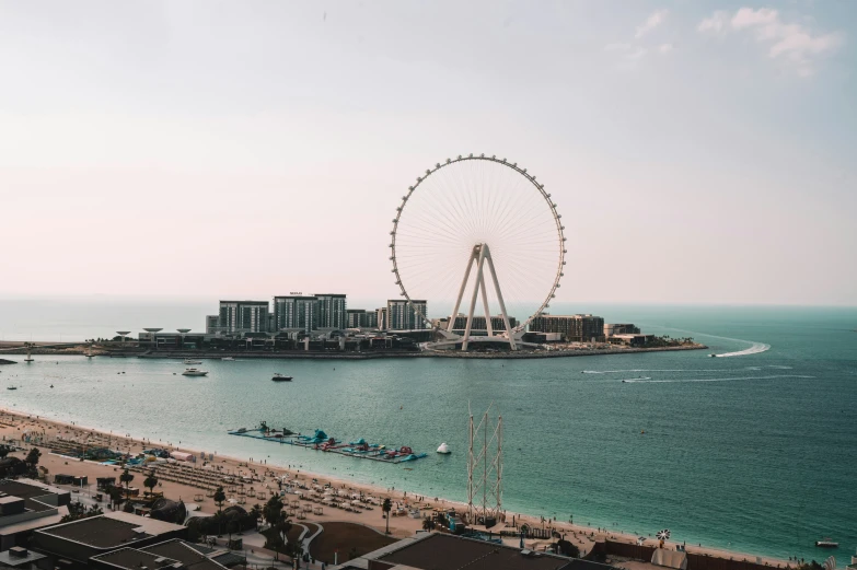 a ferris wheel in the sky over water next to buildings