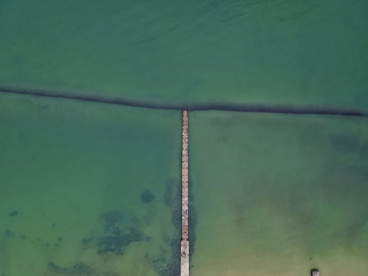 a long dock in the water with a row of boats docked at it's end