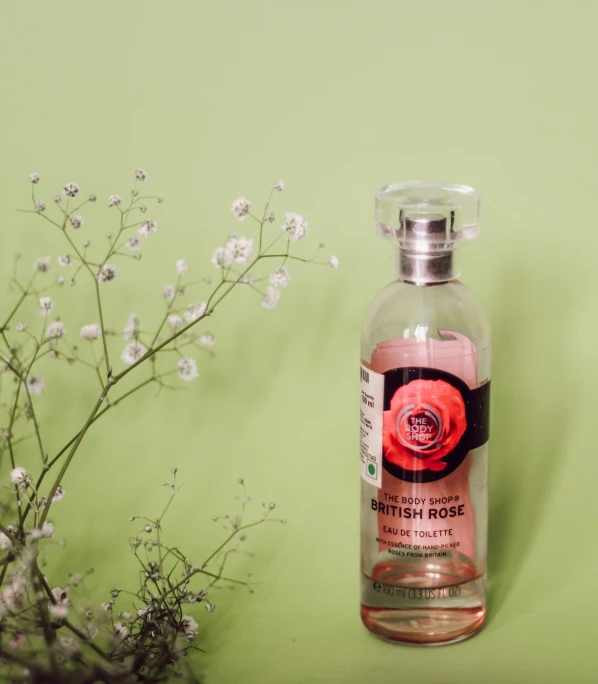 a bottle sitting on top of a shelf near flowers