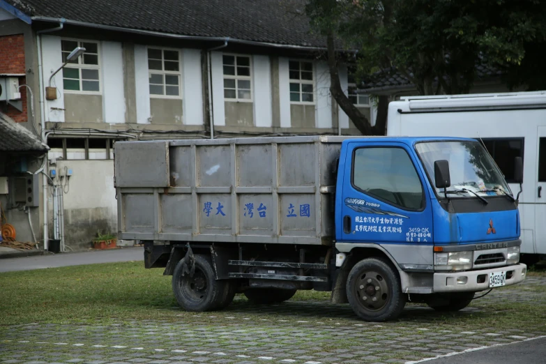 blue garbage truck parked in front of a house