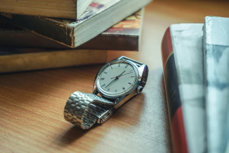 a watch sitting next to books on a desk