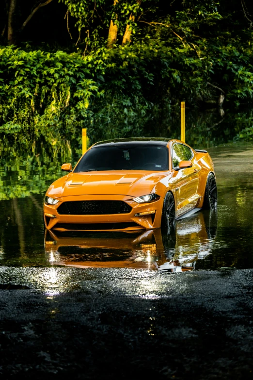 a bright yellow sports car driving through some water