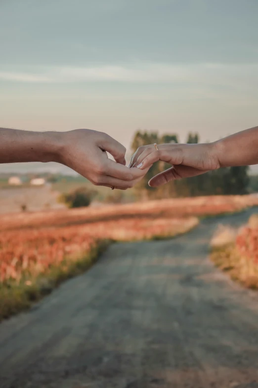 two people holding hands over a dirt road