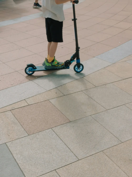 a child riding a small scooter on a sidewalk