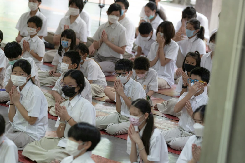 there are many children in front of a group of adults wearing masks