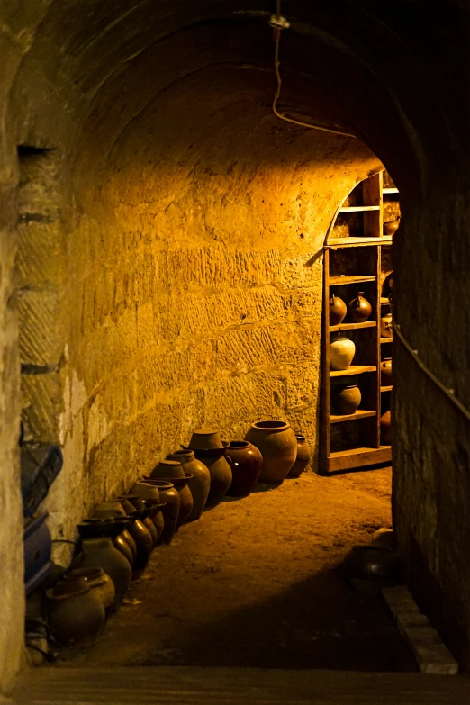 a narrow tunnel with several pots and shelves