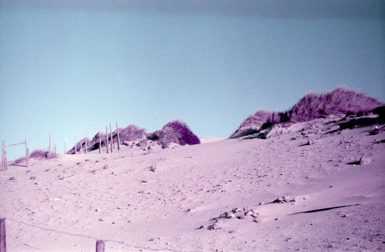 a hill covered in lots of sand with a fence in front