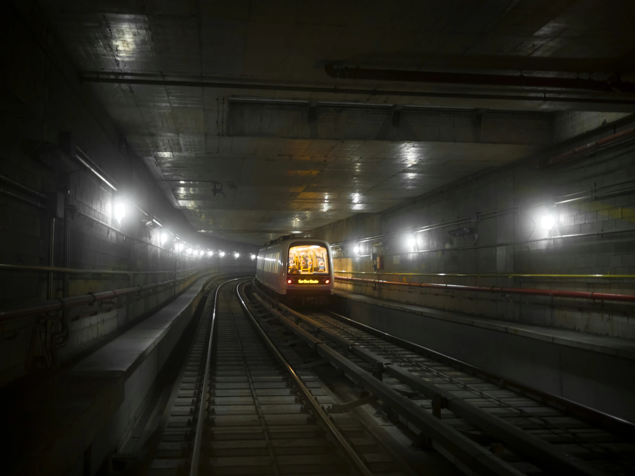 subway tracks in a dark tunnel with some lights