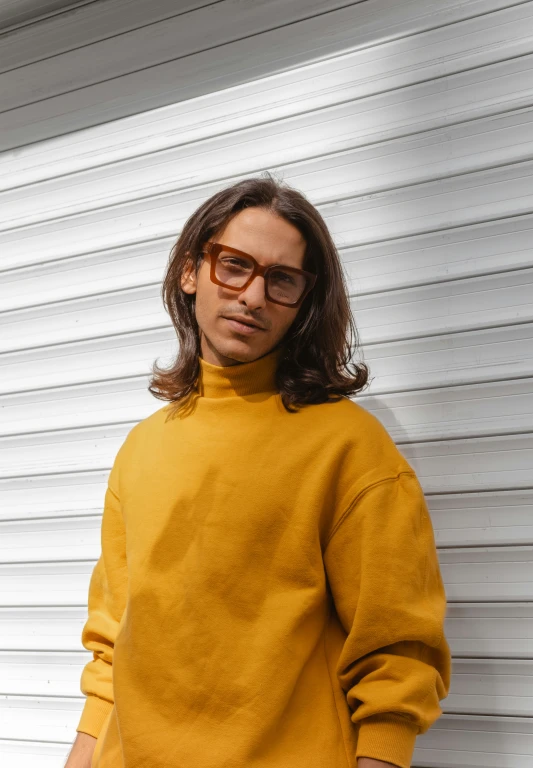 a man with long hair wearing glasses poses for the camera