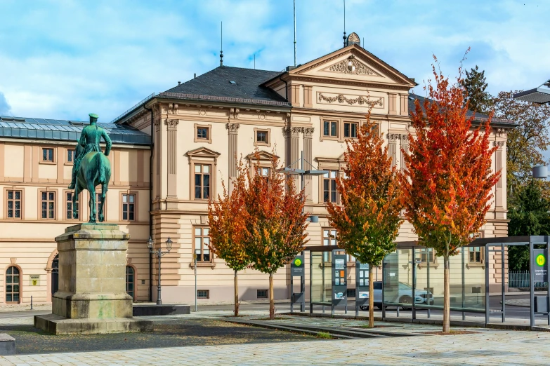 the exterior of an old government building with red and green trees