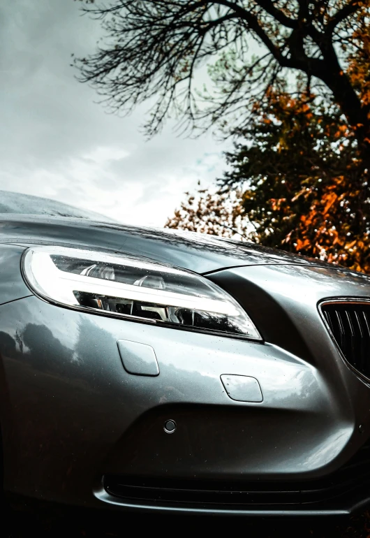 a car with the front grill open and it is sitting in front of some trees