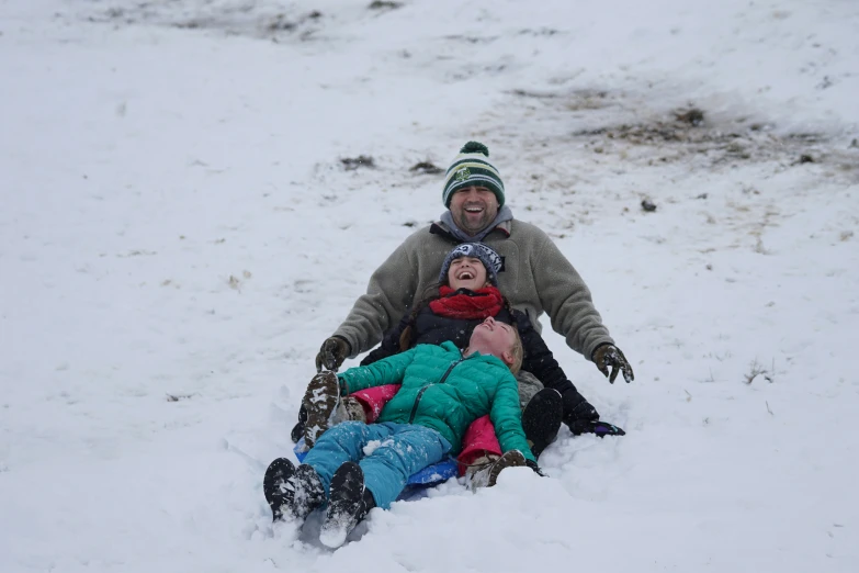 a man and young children ride in the snow