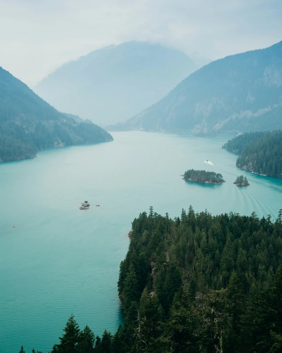 a lake with boats floating in it and mountains behind it