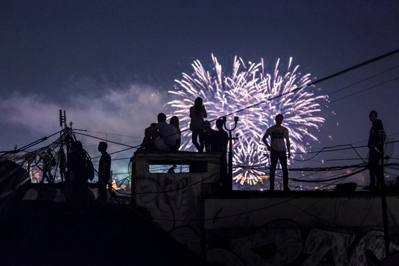 people stand at the top of a wall watching fireworks