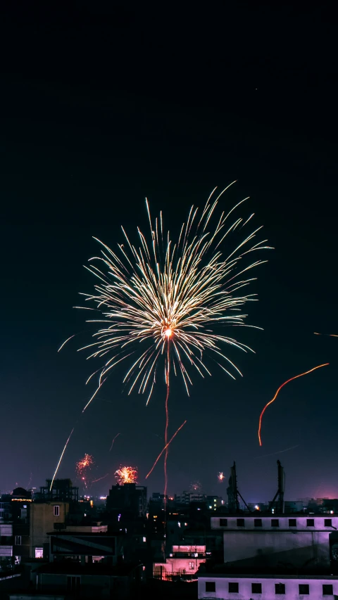 fireworks fly across the sky over buildings on the city