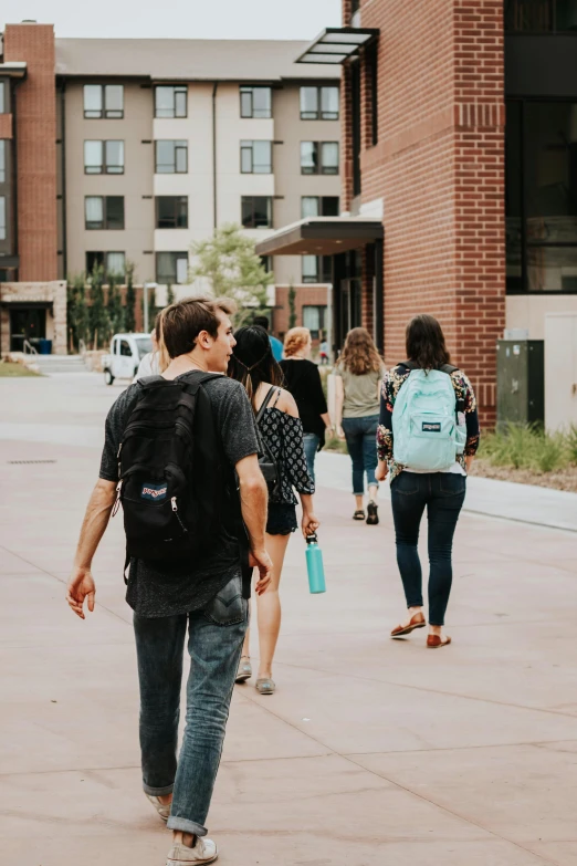 a group of people walking down a street next to tall buildings